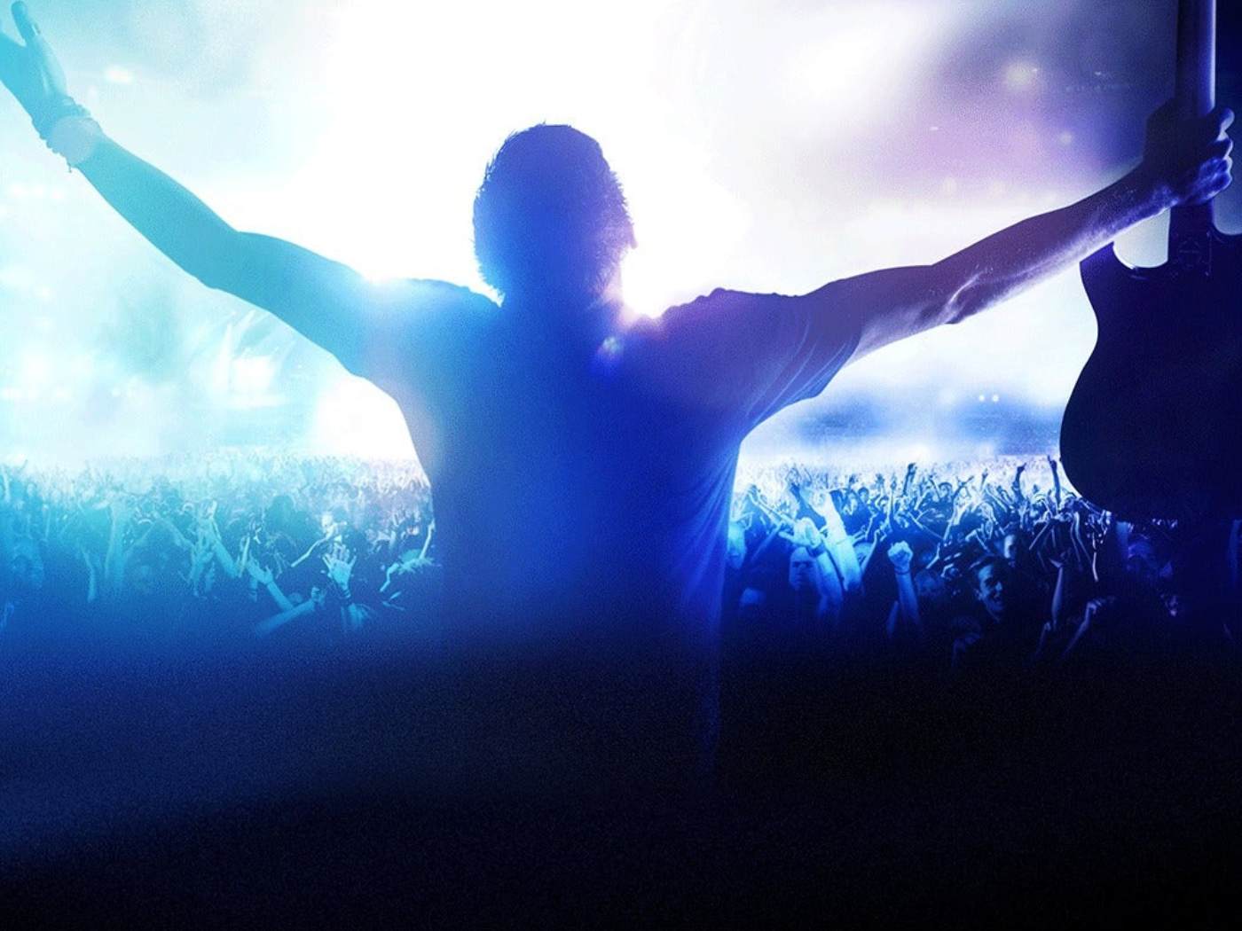 Un homme qui tend les bras dans un concert et des lumières bleutées